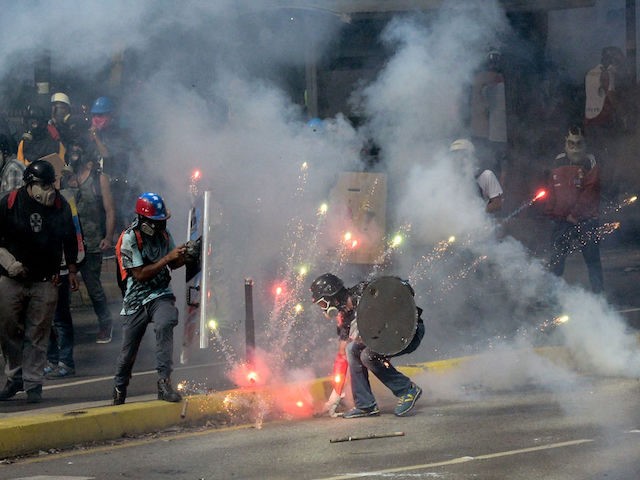 TOPSHOT - Demonstrators clash with riot police during a protest against the government of President Nicolas Maduro in Caracas on May 20, 2017. Venezuelan protesters and supporters of embattled President Nicolas Maduro take to the streets Saturday as a deadly political crisis plays out in a divided country on the …