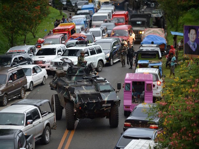 An armoured personnel carrier manuevers past gridlocked vehicles of residents fleeing Mara
