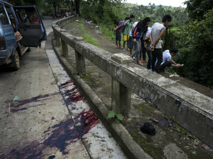 MARAWI CITY, PHILIPPINES - MAY 28: Residents view unidentified bodies believed to be executed by armed militants and dumped in a ditch as blood stains are seen on the pavement of a road on May 28, 2017 in Marawi city, southern Philippines. The 8 men, who were hogtied and executed …