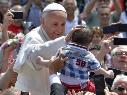 Pope Francis blesses a child as he leaves in his papamobile after the Holy mass with the e