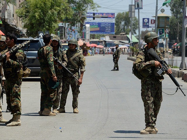 Afghan security forces stand at the site of suicide bombing in Jalalabad on May 17, 2017. Suicide bombers stormed the national television station in the eastern Afghan city of Jalalabad on May 17, triggering gunfights and explosions as journalists remained trapped inside the building, officials and eyewitnesses said. At least …