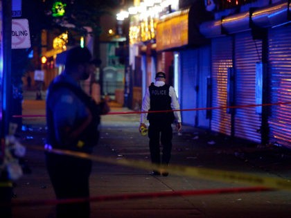 Chicago Police officers stand at the crime scene where a man was shot in the 7100 block of
