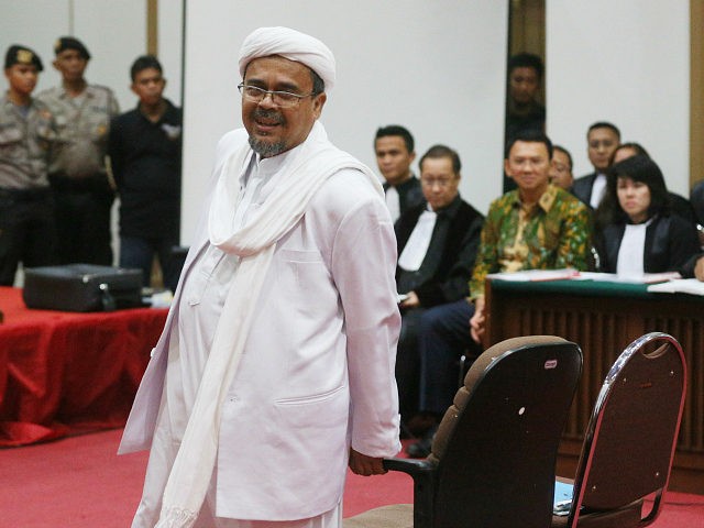 Indonesian firebrand cleric Rizieq Shihab (front) prepares to take his seat in court to te