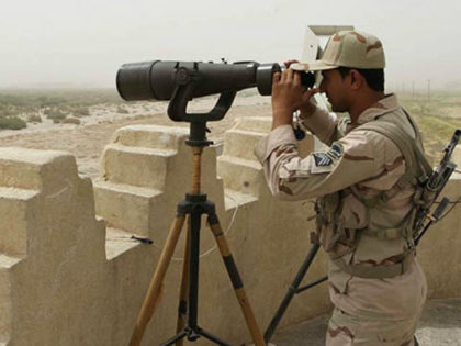 An Iranian border guard looks through a pair of binoculars to monitor a border area for dr