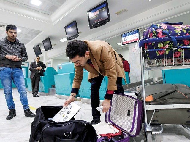 A Libyan traveller packs his laptop in his suitcase before boarding his flight for London