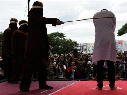 BANDA ACEH, INDONESIA - MAY 23: An Indonesian man gets caning in public from an executor known as 'algojo' for having gay sex, which is against Sharia law at Syuhada mosque on May 23, 2017 in Banda Aceh, Indonesia. The two young gay men, aged 20 and 23, were caned …