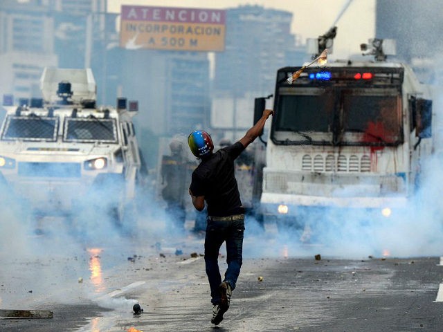 TOPSHOT - Opposition activists and riot police clash during a protest against President Nicolas Maduro, in Caracas on May 8, 2017. Venezuela's opposition mobilized Monday in fresh street protests against President Nicolas Maduro's efforts to reform the constitution in a deadly political crisis. Supporters of the opposition Democratic Unity Roundtable …