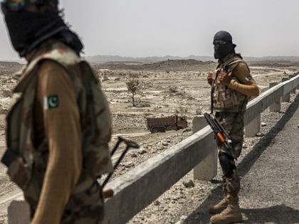 Members of the security forces observe operations at a site where workers gather materials for the construction of the M8 motorway on the outskirts of Gwadar, Balochistan, Pakistan, on Wednesday, Aug. 3, 2016. Gwadar is the cornerstone of Chinese President Xi Jinping's so-called One Belt, One Road project to rebuild …