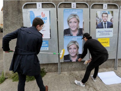 Members of French far-right party Front National Youth Movement (FNJ) party stick posters of French far-right Front National (FN) party candidate for the presidential election Marine Le Pen on April 27, 2017 in Ajaccio, on the French Mediterranean island of Corsica. / AFP PHOTO / PASCAL POCHARD-CASABIANCA (Photo credit should …
