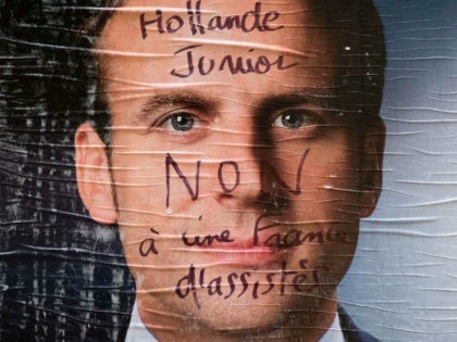 An electoral poster of French presidential election candidate for the En Marche ! movement Emmanuel Macron is covered with a graffiti reading 'Hollande Junior, no to a France of assisted people' in Paris, on May 2, 2017. / AFP PHOTO / JOEL SAGET (Photo credit should read JOEL SAGET/AFP/Getty Images)