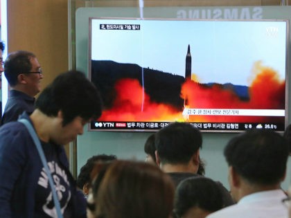 People watch a TV news program showing a file image of a missile launch by North Korea, at