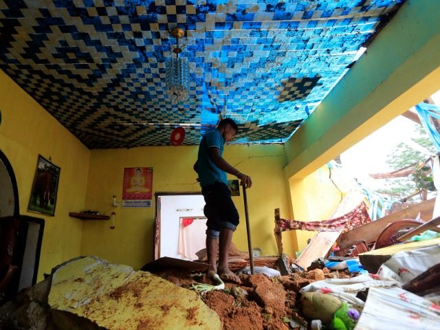 A Sri Lankan mudslide survivor salvages belongings at a destroyed house in Kiribathgala,