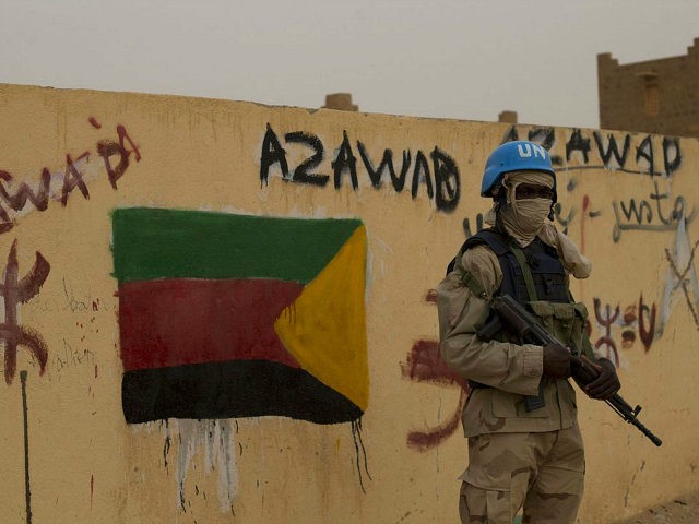 FILE - In this Sunday, July, 28, 2013 file photo, a United Nations peacekeeper stands guard at the entrance to the main polling station, covered in separatist flags and graffiti supporting the creation of the independent state of Azawad, in Kidal, Mali. Mali's new president-elect Ibrahim Boubacar Keita, whose rival …