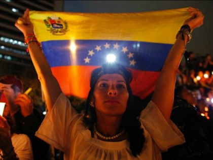 A demonstrator holds a Venezuelan flag during a vigil for the victims of the clashes with