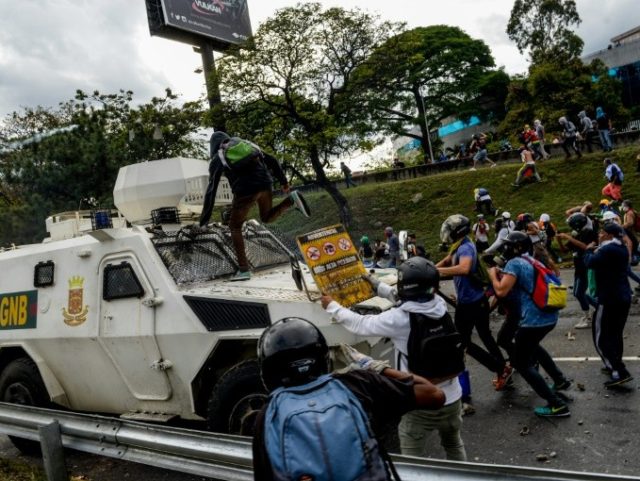 Venezuelan opposition activists confront a police armoured vehicle during a protest against President Nicolas Maduro, in Caracas, on May 1, 2017