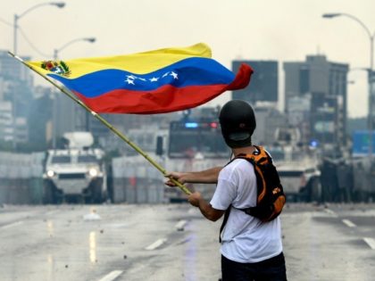 A Venezuelan opposition demonstrator waves a national flag in front of the riot police dur
