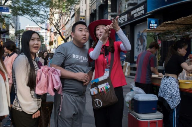 A guide directs tourists in Seoul, the capital of South Korea, which has experienced a plu