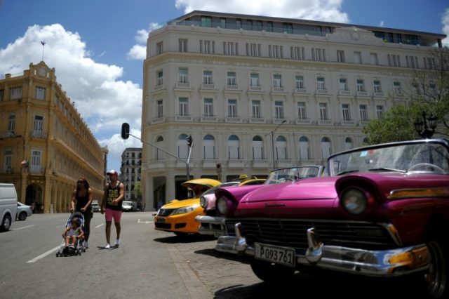 Cubans walk near the Manzana Kempinski Hotel, the first ultra luxury hotel in Cuba, on May