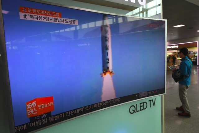 A man walks past a television showing a news report on North Korea's latest missile test i