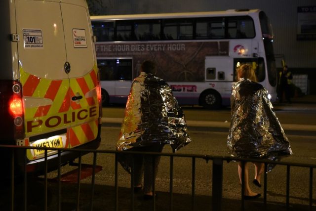Concert goers wait to be picked up after a suspected terror attack during a pop concert by