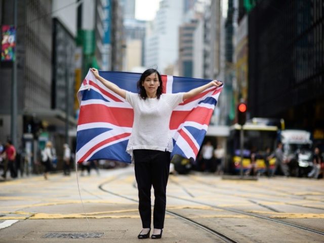 Designer Alice Lai, 39, holds a British Union Jack flag on a main road in Hong Kong. Almos