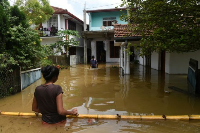 Sri Lankan residents make their way through floodwaters in Kaduwela. Emergency teams are r