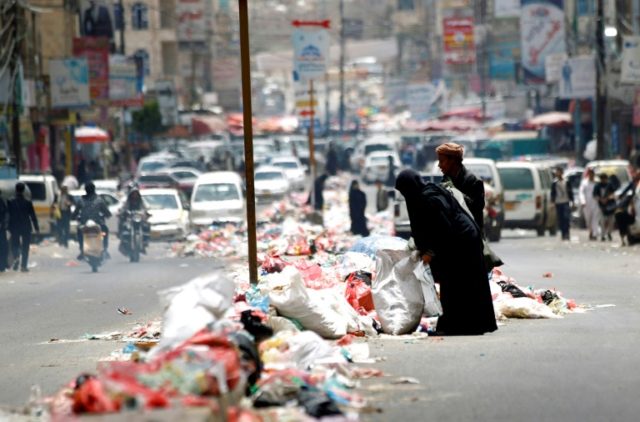 Yemenis salvage for discarded items in piles of rubbish lining a road in Sanaa on May 9, 2