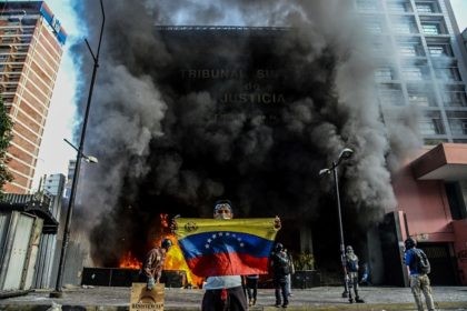 TOPSHOT - Anti-government demonstrators attack the administration headquarters of the Supreme Court of Justice as part of protests against President Nicolas Maduro in Caracas, on June 12, 2017. With Venezuelans suffering from high inflation, food shortages and soaring crime rates, plus a deepening corruption scandal, the Venezuelan opposition has mounted …