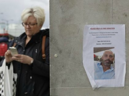 A woman walks by a poster of a missing man …