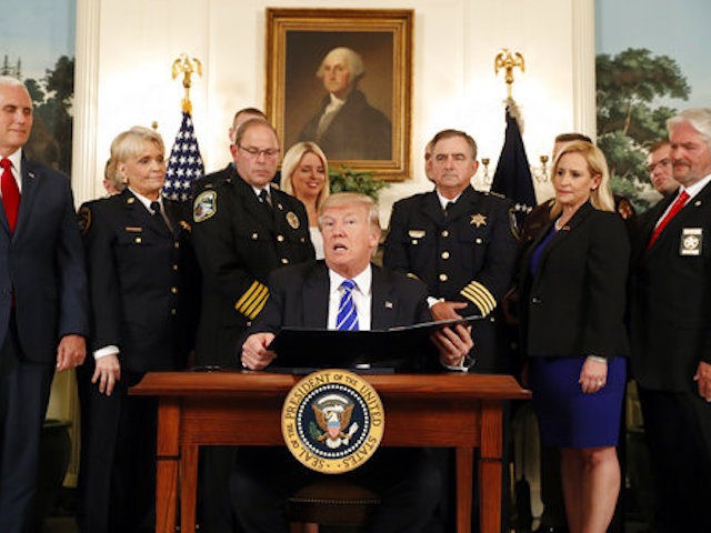 President Donald Trump, with Vice President Mike Pence, left, is flanked by members of law