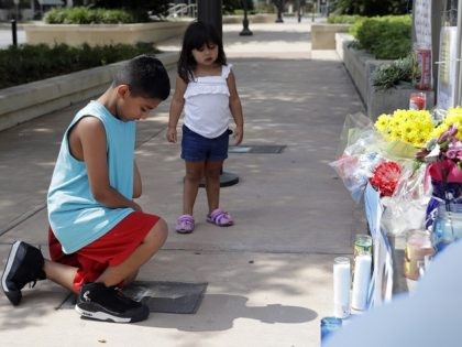 Tony Alameda, left, prays after placing flowers at a make-shift memorial at the San Antonio Police headquarters, Friday, June 30, 2017, in San Antonio. Two San Antonio police officers were wounded critically and a suspect was killed in a shootout on a street just north of the city's downtown section. …