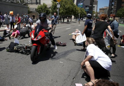 SAN FRANCISCO, CA - JUNE 21: A motorcyclist rides through dozens of healthcare activists who were blocking a street while staging a die-in as the protested the Trumpcare bill on June 21, 2017 in San Francisco, California. The man narrowly missed the protesters on Seventh Street. Dozens of healthcare activists …