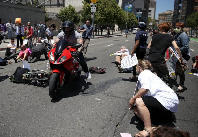 SAN FRANCISCO, CA - JUNE 21: A motorcyclist rides through dozens of healthcare activists