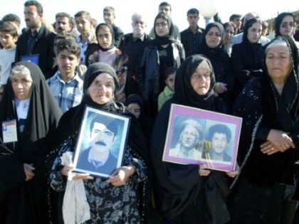 Kurds holds pictures of dead relatives during the anniversary ceremony at the memorial sit