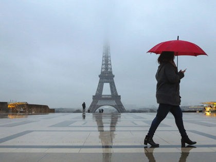 People with umbrellas walk on the human rights plaza in front of the Eiffel tower during a rainy morning in Paris on February 7, 2017. / AFP / Ludovic MARIN (Photo credit should read LUDOVIC MARIN/AFP/Getty Images)