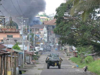 In this file photo, a Philippine Marines armored personnel carrier speeds away as black smoke billows from burning houses after military helicopters fired rockets at militant positions in Marawi City on May 30, 2017. File photo by Ted Aljibe/AFP