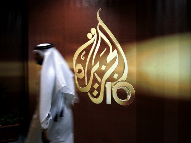 FILE -- In this Nov. 1, 2006 file photo, a Qatari employee of Al Jazeera Arabic language TV news channel walks past the logo of Al Jazeera in Doha, Qatar. Hackers allegedly broke into the website of Qatar's state-run news agency and published a fake story quoting the ruling emir, …