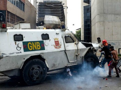 TOPSHOT - A Venezuelan National Guard riot control vehicle runs over an opposition demonstrator during a protest against Venezuelan President Nicolas Maduro, in Caracas on May 3, 2017. Venezuela's angry opposition rallied Wednesday vowing huge street protests against President Nicolas Maduro's plan to rewrite the constitution and accusing him of …