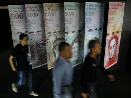 People walk by banners of Venezuelan bolivar notes displayed at the Venezuelan Central Bank building in Caracas, Venezuela May 23, 2017. REUTERS/Carlos Barria