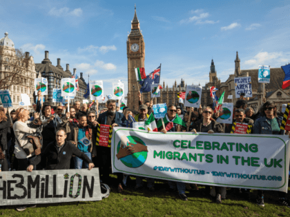 Protesters and migrant workers hold banners and flags as they demonstrate outside Parliame