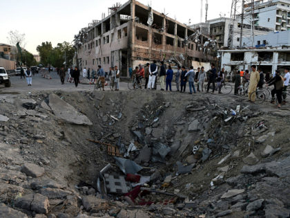 TOPSHOT - Afghan security forces and residents stand near the crater left by a truck bomb