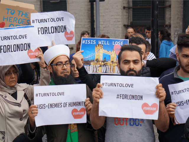 Muslims hold signs saying "ISIS WILL LOSE" and "#TURNTOLOVE" on Sunday June 4, 2017 at the police cordon surrounding the site in south London of the deadly van-and-knife attack that killed several people on Saturday night. (AP Photo/Raphael Satter)
