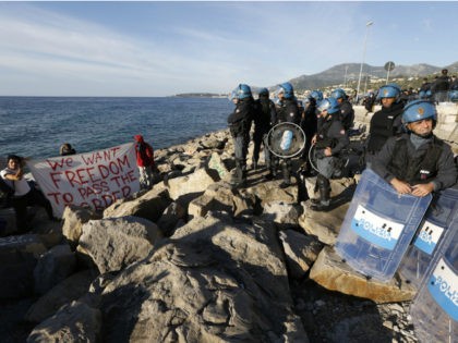 Two migrants hold a banner reading 'We want freedom to pass the border' as they