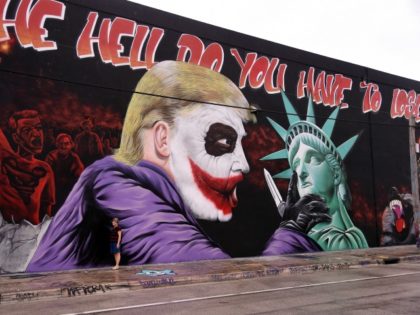 TOPSHOT - A woman poses for a photo in front of a Donald Trump mural covering a building in the Wynwood neighbourhood of Miami, Florida, on October 27, 2016. The Anti-Trump, batman themed mural was created by the artists of the Bushwick Collective ahead of the US presidential election. / …