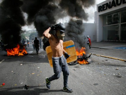 An anti-government demonstrator walks past two National Guard soldiers' motorcycles that w