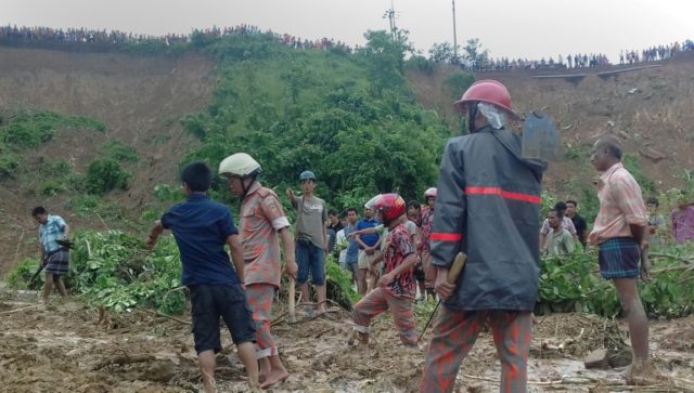 Bangladeshi firefighters and volunteers are watched by bystanders as they search for bodie