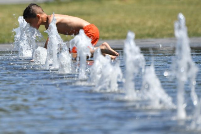 A boy plays in a public fountain as Meteo France has placed 16 departments on orange alert