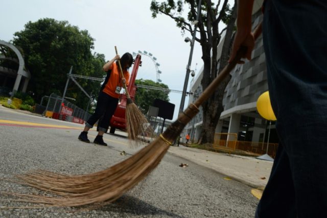 Singaporean volunteers sweep a public area inside the circuit of the Formula One Grand Pri