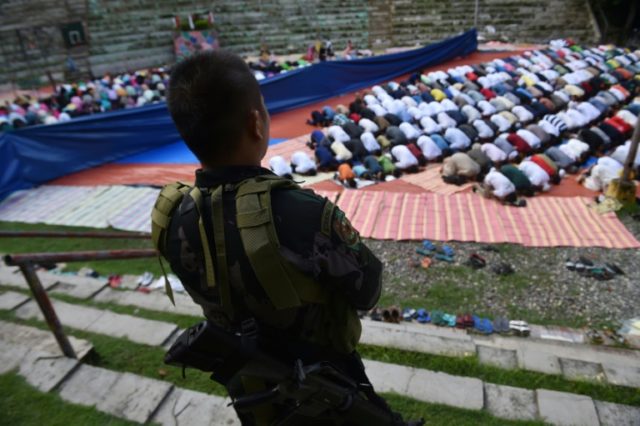 A member of the police special action force stands guard as Muslims, who fled the conflict