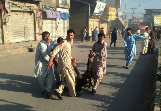 Pakistani residents carry an injured man after a twin blasts at a market in northwest Paki